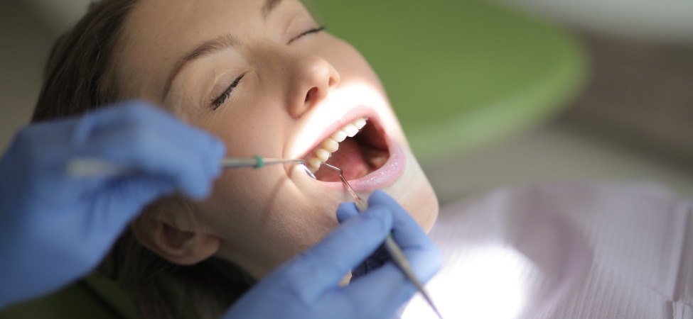Mulher branca com olhos fechados fazendo procedimento nos dentes