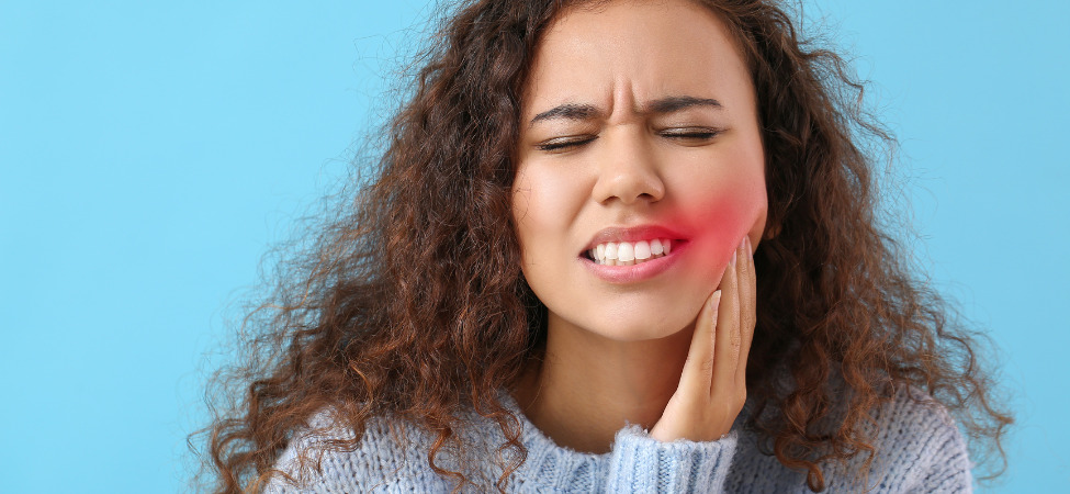 Mulher branca de cabelo cacheado sentindo dor na boca no lado direito